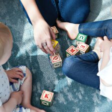 A group of people sitting on the floor playing with blocks.