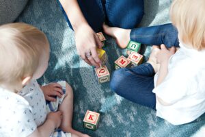 A group of people sitting on the floor playing with blocks.