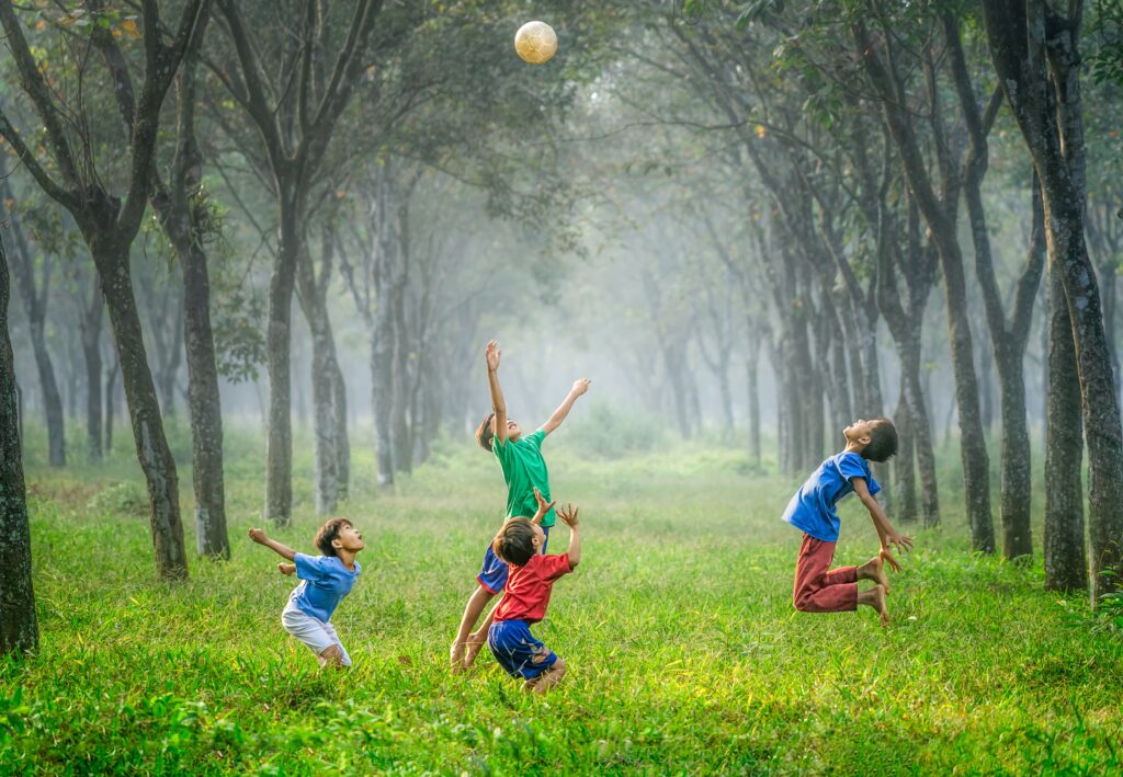 A group of kids playing with a ball in the grass.