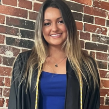 A woman standing in front of a brick wall.