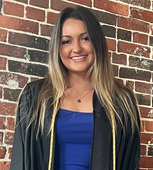 A woman standing in front of a brick wall.